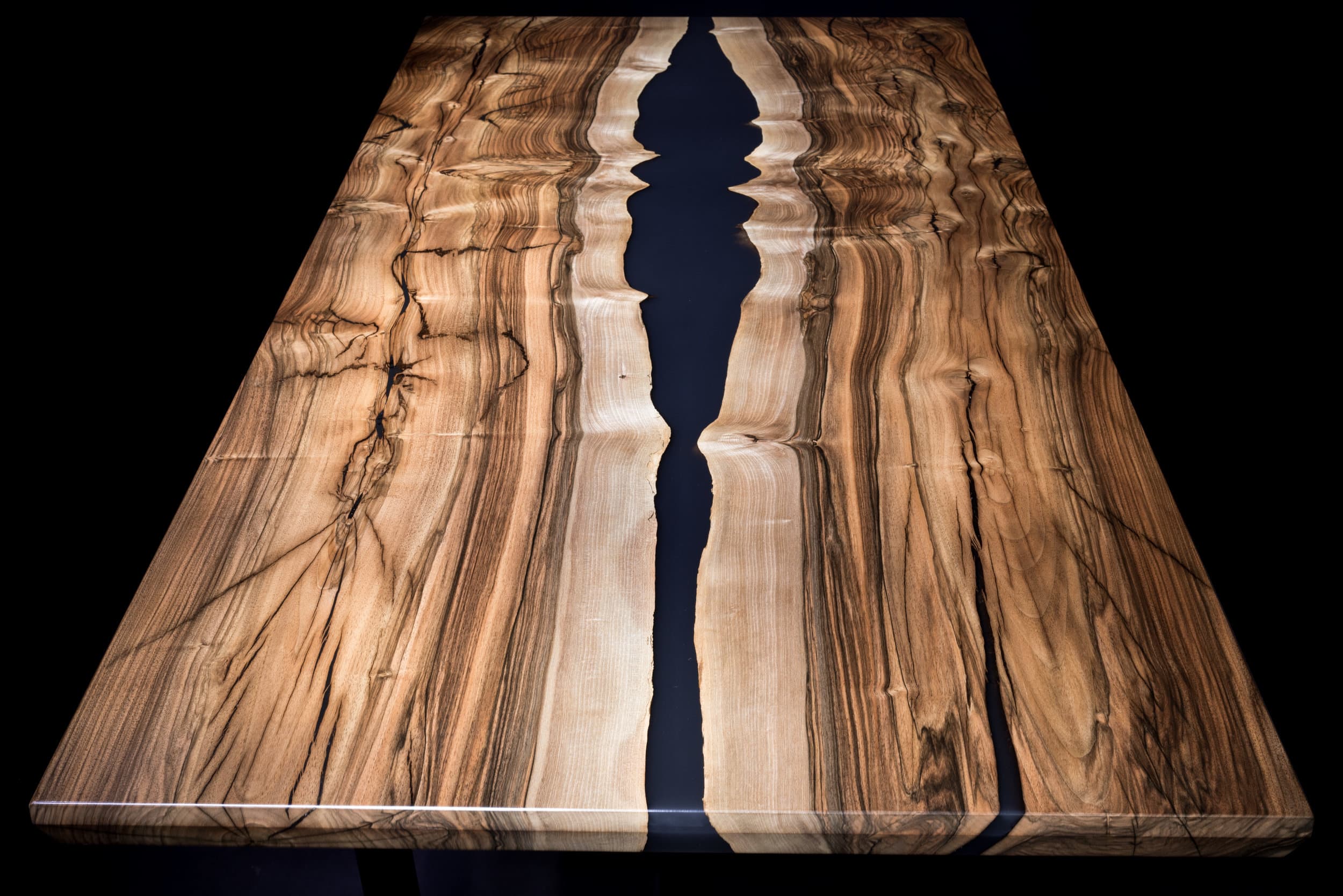A finished epoxy river table from above: English walnut with pale sapwood edges around a black resin river